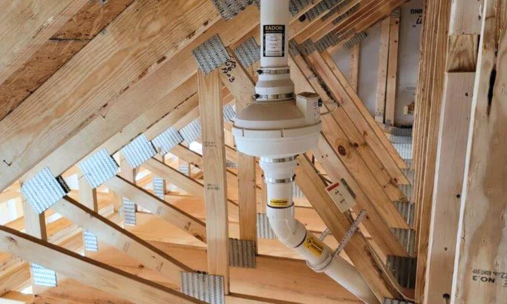 Radon fan mounted in an attic, routing the vent pipe up and out through the roof